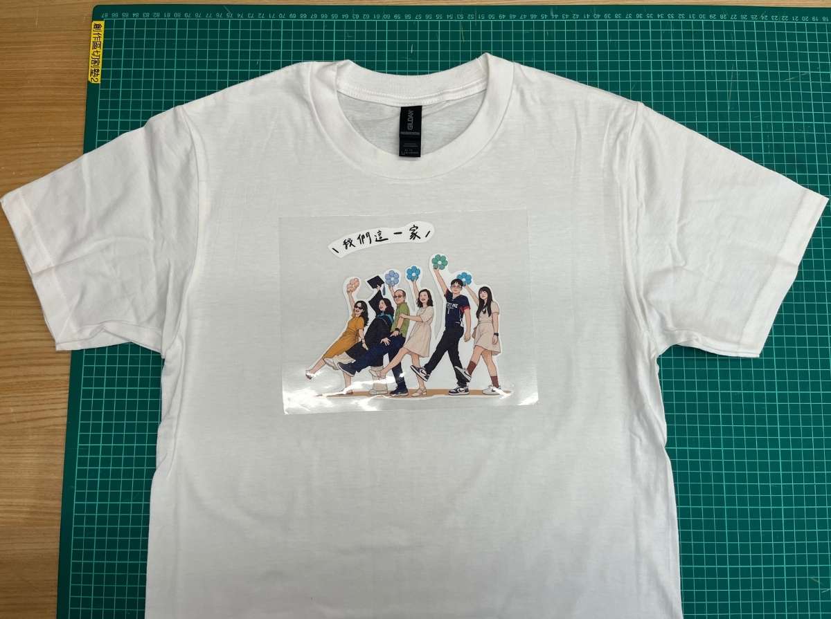 Family illustration transfer film placed on a white T-shirt to check the printing position before heat pressing.