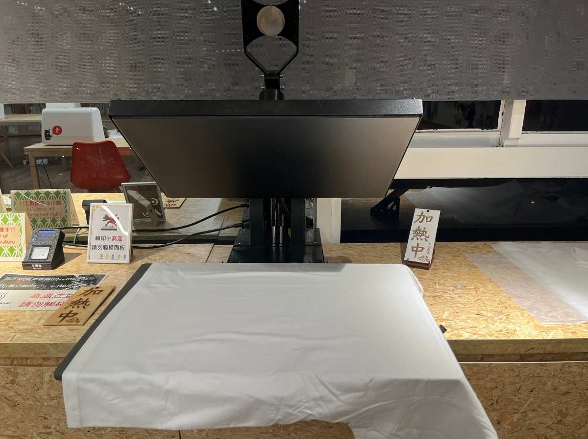 White T-shirt being pressed with a heat press machine to smooth the fabric before transfer printing.